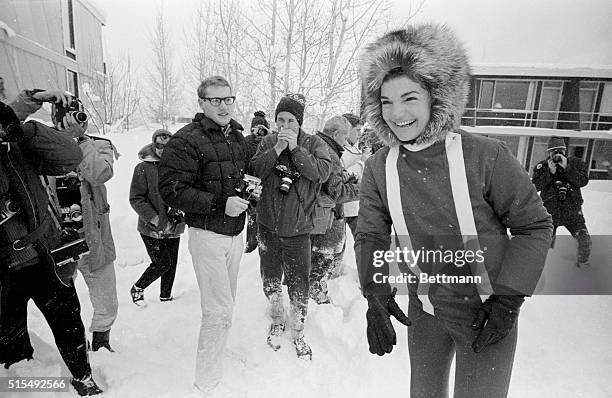 Besieged by photographers, Jacqueline Kennedy calls to her children playing in the snow during a vacation in Aspen.