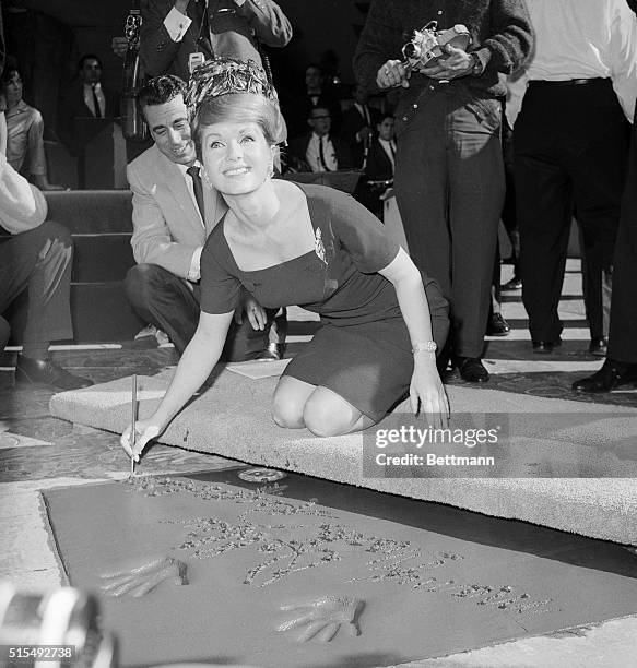 Actress Debbie Reynolds signs her name in the wet cement in the forecourt of Grauman's Chinese Theater. She became part of Hollywood history and was...