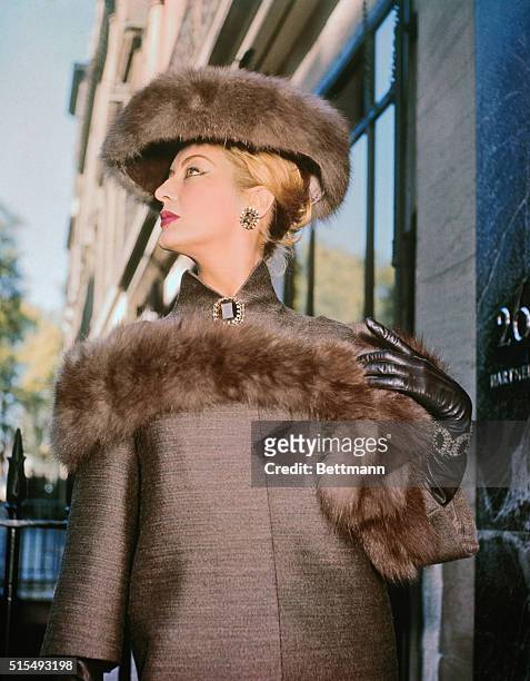 Norman Hartnell fashion from London...Vixen, modeled by Cynthia, is a three-tiered dress and coat of tobacco brown satin faced mohair. It is worn...