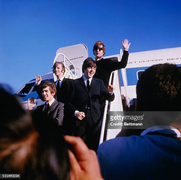 The Fab Four wave to fans and journalists as they disembark their Pan American flight onto the tarmac at San Francisco International Airport.