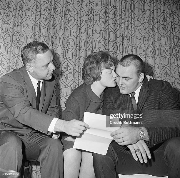 All-American Center Dick Butkus of Illinois gets a big kiss from his wife Helen after signing with Chicago Bears here 12/3, as George Halas, Jr.,...