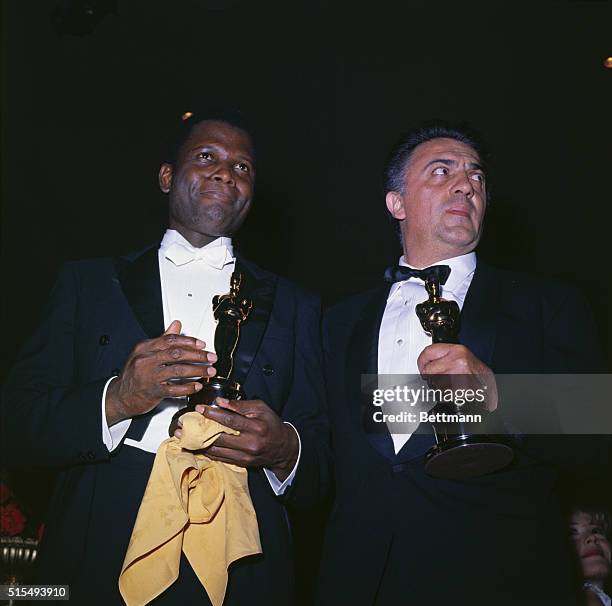Italian Director Federico Fellini, with actor Sidney Poitier at the Academy Awards party following presentations. The hold Oscars.