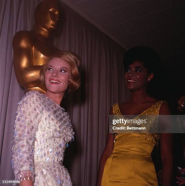Santa Monica, CA: Patti Page and Nancy Wilson stand beneath a large "Oscar" at the 37th Annual Academy Award presentations after they each sang one...