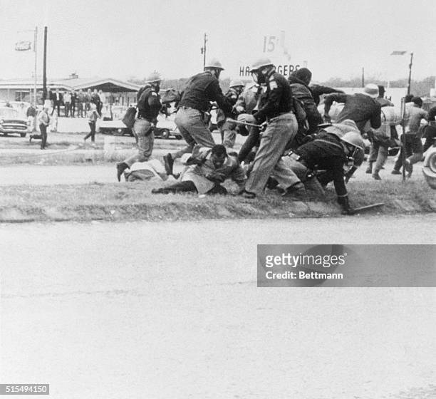 Selma, Alabama: End Of The March. SNCC leader John Lewis , attempts to ward off the blow as a burly state trooper swings his club at Lewis' head...