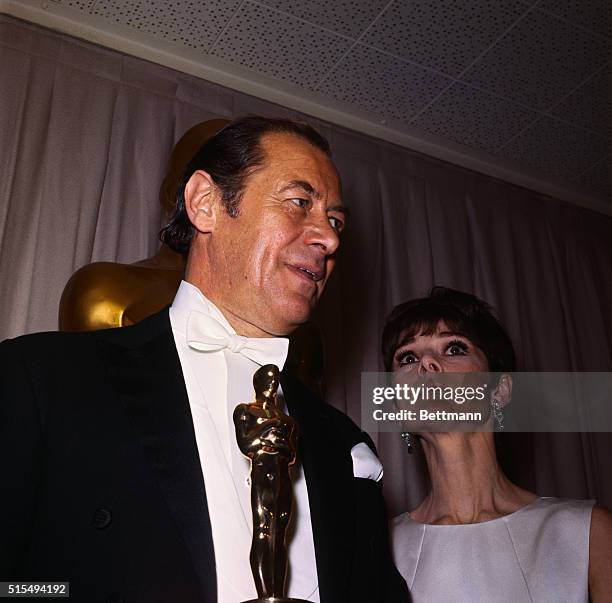 Debonair Rex Harrison holds the Oscar that he won at the 37th Annual Academy Awards for best performances by an actor. Mr. Harrison won the award for...