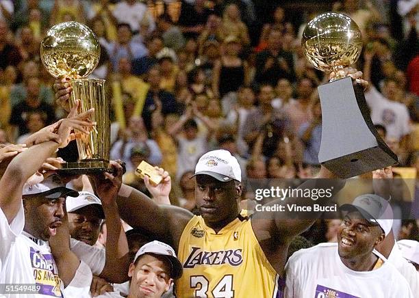 Shaquille O'Neal of the Los Angeles Lakers holds the MVP trophy and the Larry O'Brien Trophy for winning the NBA Championship 19 June after game six...
