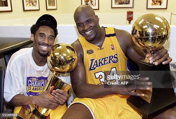 Kobe Bryant of the Los Angeles Lakers holds the Larry O'Brian trophy as teammate Shaquille O'Neal hold the MVP trophy after winning the NBA...
