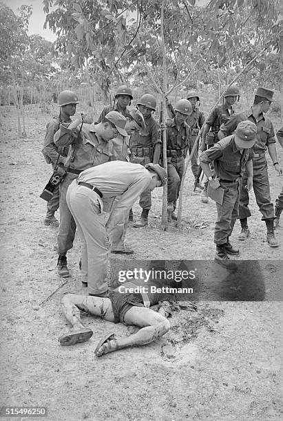 South Korean security troops look at the body of a Viet Cong guerrilla who was killed following heavy communist mortar attacks on a Korean engineers'...