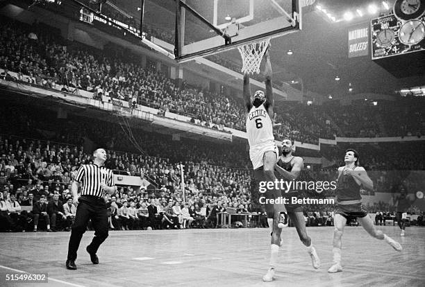 Bill Russell soars high to dunk in two points, beating out 76ers' Wilt Chamberlain and Dave Gambee during fourth quarter action at the Boston...