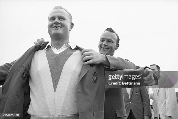 Augusta, Georgia: Jack Nicklaus gets an assist from defending Masters champion Arnold Palmer as he dons his second green coat--symbol of the Masters...