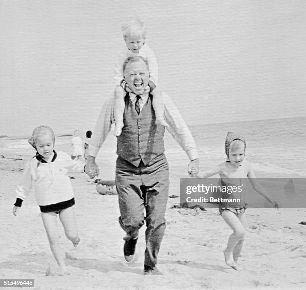 Malibu Beach, California: Mickey Rooney goes for a run down the beach here with his kids during a break in filming How to Stuff a Wild Bikini for...