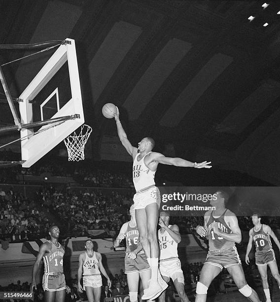 Philadelphia: 76ers' Wilt Chamberlain, jumps high as Cincinnati Royal, Jerry Lucas and Wayne Embry can only look on during first period action, March...