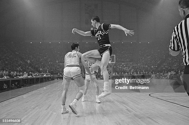 Princeton's Bill Bradley, passes under the legs of Jim Benedict of Providence, to teammate Gary Walter who scored a ten-pointer for the Tigers in the...