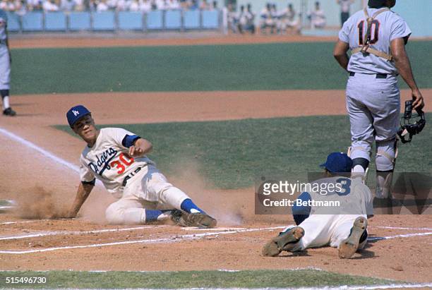Maury Wills of the Dodgers slides into home plate to score the first Dodger run in first inning of game against Minnesota Twins at Dodger Stadium...
