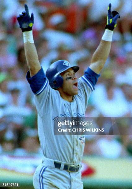 Toronto Blue Jays Roberto Alomar raises his arms as he watches the ball he just hit off of Oakland A's Dennis Eckersley sail over the right field...
