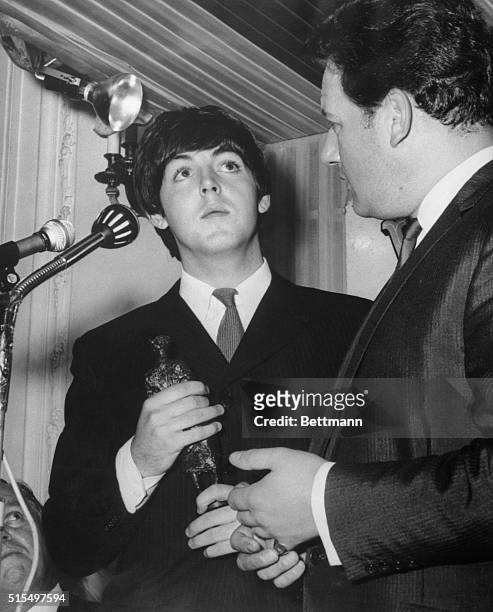 Win songwriting award...Paul McCartney of the Beatles clutches the Ivor Novello Award for songwriting after receiving it at the Variety Club of Great...