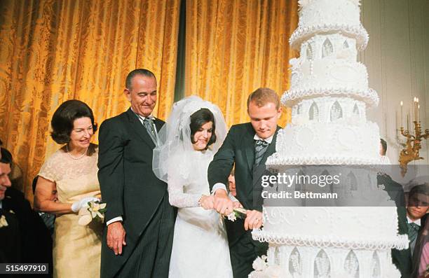 Mr. And Mrs. Pat Nugent with their wedding cake at the White House as President and Mrs. Johnson look on during the reception following Luci's...