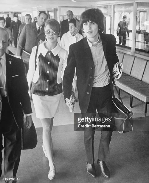 Beatle George Harrison and his wife, former model Patti Boyd, walk to their plane at London Airport February 8th at the start of a delayed honeymoon...