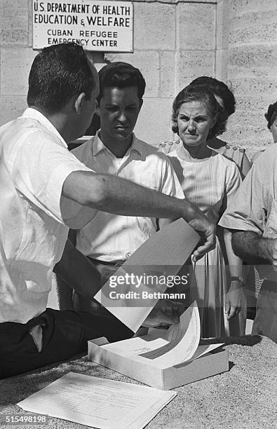 Cuban refugee worker hands out forms to waiting Cubans 10/8 at the Cuban Refugee Emergency Center. The forms are asking for information concerning...