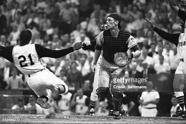 Pirates' Roberto Clemente looks up at teammate Gene Alley while sliding across the plate to score an inside the park homer in the 2nd inning of the...