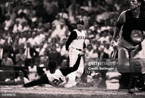 Pirates' Roberto Clemente looks up at teammate Gene Alley while sliding across the plate to score an inside the park homer in the 2nd inning of the...