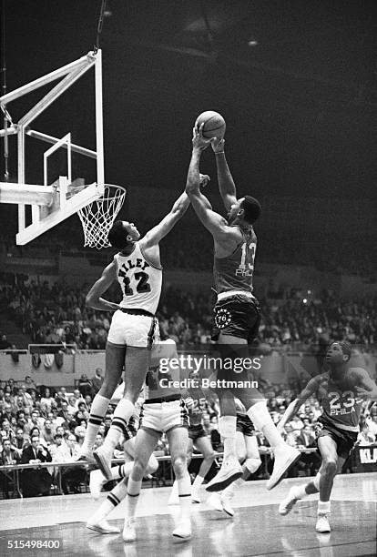 Los Angeles: Wilt Chamberlain of the Philadelphia 76ers nabs a rebound over the head and hands of the Lakers' Gene Wiley in 1st quarter of game here.