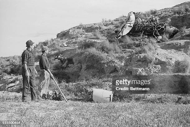 Spanish workmen look at wreckage scattered over a hillside as they assist in the search for an atomic weapon missing in the crash of an American...