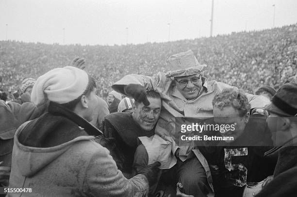 Packer Coach Vince Lombardi is hoisted triumphantly to the shoulders of two of his backfield stars, fullback Jim Taylor and halfback Paul Hornung...