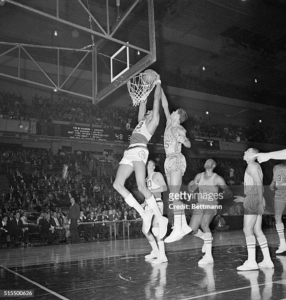 New York: St. Louis Hawks' Jim Washington follows Philadelphia 76ers' Wilt Chamberlain right up to the basket but can't stop him from stuffing in two...