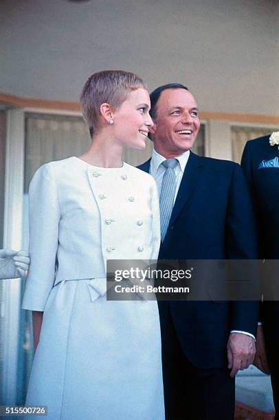 Frank Sinatra and Mia Farrow are shown outside the sands Hotel, following their wedding. Standing with them is Mrs. William Goetz, who served as...