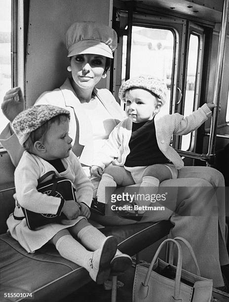 Trousered actress Joan Collins, prepares to depart from London Airport for Hollywood with her children Tara, and Sacha, 11 months. The happy trio...