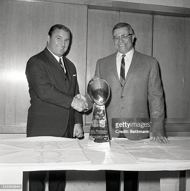 Green Bay Packers head coach Vince Lombardi and Kansas City Chiefs head coach Hank Stram shake hands as they view the Super Bowl Trophy their teams...