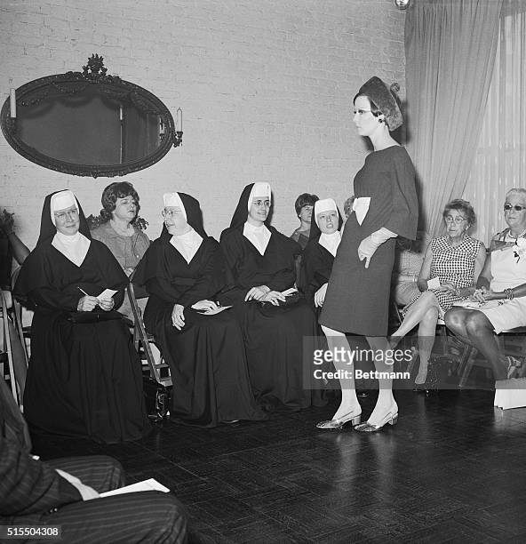 Three nuns, all members of the faculty at Mt. Mary College in Milwaukee, Wisconsin, look over one of the models at the viewing, June 8, of the fall...
