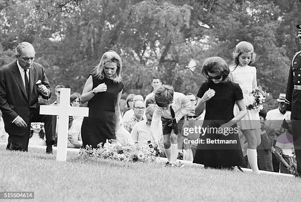 Jacqueline Kennedy and her children, Caroline and John Jr., kneel in prayer at the grave of the late President Kennedy after attending burial rites...