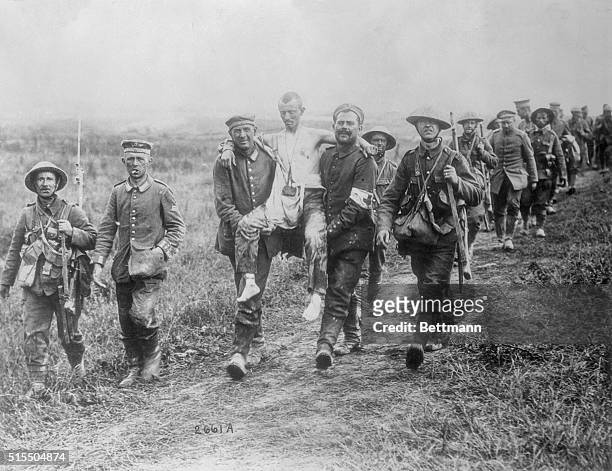 German prisoners carry their own wounded away for treatment, under the escort of British soldiers with rifles and bayonets. Note how the unwounded...