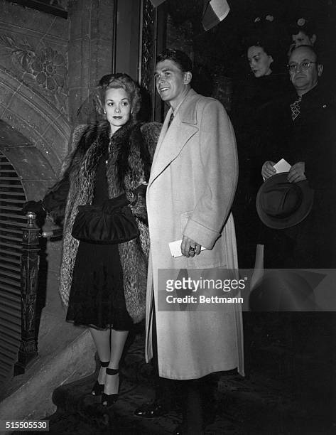 Jane Wyman, accompanied by husband, Ronald Reagan, appeared at the Academy Award dinner in a mid-calf length dinner dress of black chiffon and lace...