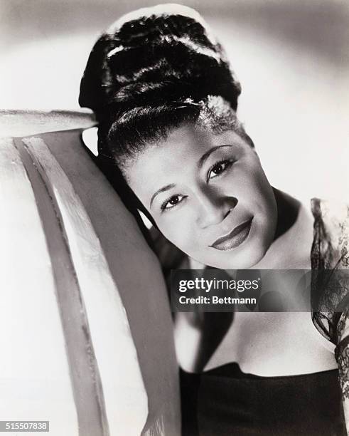 Head and shoulders photo of a young Ella Fitzgerald, wearing her hair up in a large bun and leaning to the left.