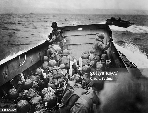 French Coast Dead Ahead. Helmeted Yankee soldiers crouch, tightly packed, behind the bulwarks of a Coast Guard landing barge in the historic sweep...