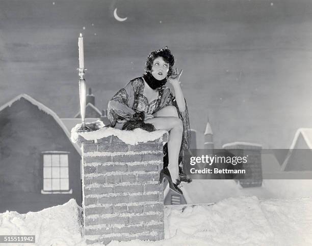 Actress Clara Bow sits on a chimney with a candle listening for the arrival of Santa Claus in and unidentified Paramount Pictures' film. Undated...