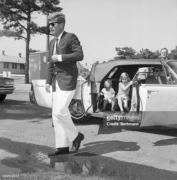 President John F. Kennedy walks out of a car with his children Caroline and John Jr. Following him toward a hospital where they are visiting his wife...