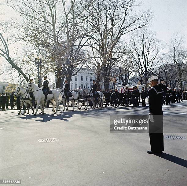 The caisson carrying the flag-draped coffin of President John F. Kennedy leaves the White House grounds on its slow journey to the Capitol Rotunda.