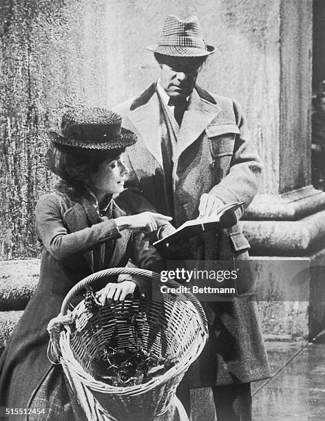 Sheltered from artificial rain on Warner Brother's sound stage, Audrey Hepburn and Rex Harrison study script on first day of shooting for My Fair...