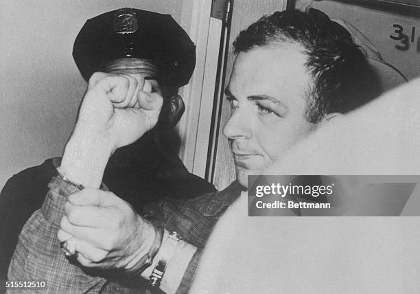 Lee Harvey Oswald wears handcuffs after Dallas police arrest him as the prime suspect in the Assassination of President John F. Kennedy.