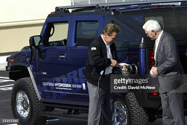 California Governor Arnold Schwarzenegger fills up the first hydrogen-powered H2 Hummer as General Motors chairman Bob Lutz looks on during the...