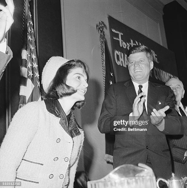 President John F. Kennedy applauds as his wife is introduced at a Chamber of Commerce breakfast, November 22nd. Later in the day, an assassin firing...