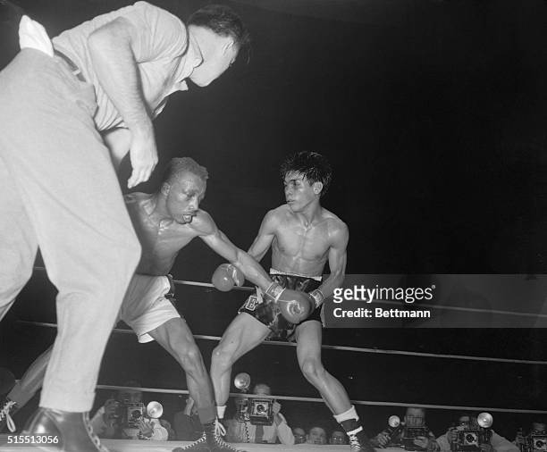 Featherweight champ Sandy Saddler reaches to the canvas for his mouthpiece in the eight round as challenger Gabriel Elorde of the Philippines moves...