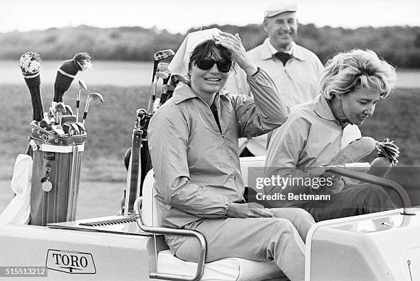 Mrs. Jacqueline Kennedy pushes her hair back as she watched the President drive off the tenth tee during a round for the weekend at the home of Mrs....