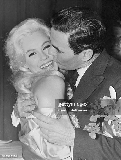 Shapely Mamie Van Doren gets a kiss from an admirer, Carlos Estrada, , at a party celebrating the start of production on her new film, A Blonde From...