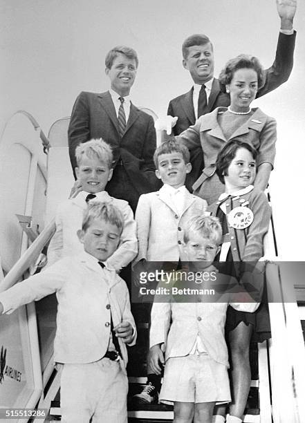 Democratic presidential nominee, John F. Kennedy waves as he boards a plane enroute to his Massachusetts home. On the ramp with Kennedy are Robert...