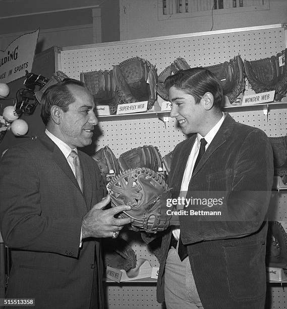 New York Mets coach Yogi Berra , who spent many years catching for the New York Yankees, helps his son Larry try on a special "Yogi Berra Catcher's...